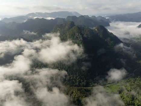Aerial view of the karst mountains and dense forests of Phong Nha Ke Bang National Park shrouded in morning mist and low clouds Quang Binh Province Vietnam. Aerial view of the karst mountains and dense forests of Phong Nha Ke Bang National Park shrouded in morning mist and low clouds Quang Binh Province Vietnam.
