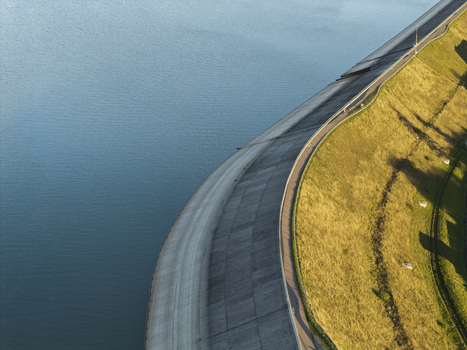 Aerial view of Lake Czorsztynskie dam with its concrete wall and grassy embankment bordering the blue reservoir Nowy Targ Lesser Poland Voivode Poland.