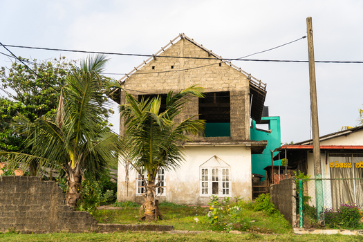 View of a two story building under construction with unfinished concrete blocks and palm trees in Galle Southern Province Sri Lanka.