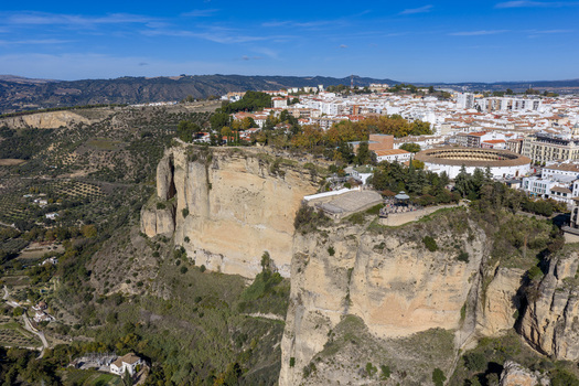Aerial view of the historic town of Ronda perched on the edge of the El Tajo gorge featuring the iconic bullring white buildings and rugged cliffs in Ronda Andalusia Spain. Aerial view of the historic town of Ronda perched on the edge of the El Tajo gorge featuring the iconic bullring white buildings and rugged cliffs in Ronda Andalusia Spain.