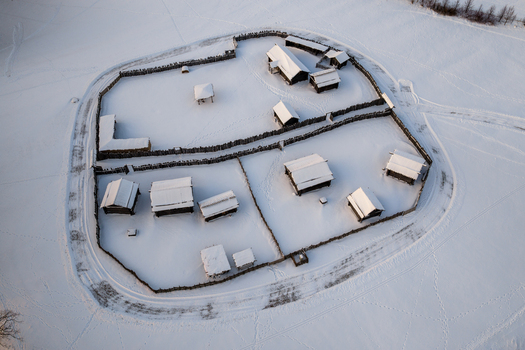 Aerial view of the reconstructed medieval wooden settlement with snow covered rooftops and fences in Kernave Vilnius County Lithuania.