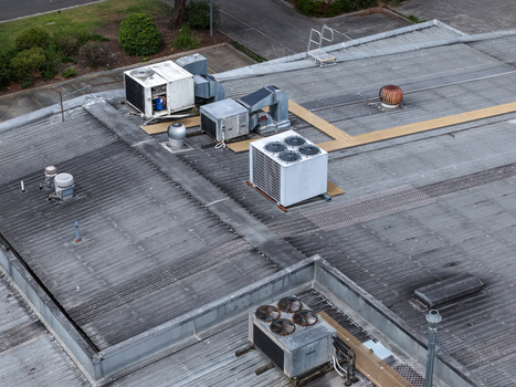 Aerial view of industrial rooftop featuring multiple HVAC units ventilation systems and corrugated metal surfaces in Melbourne VIC Australia.
