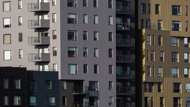 Aerial view of a modern apartment complex featuring contrasting grey black and bronze facades with balconies and glass windows in Iceland. Aerial view of a modern apartment complex featuring contrasting grey black and bronze facades with balconies and glass windows in Iceland.