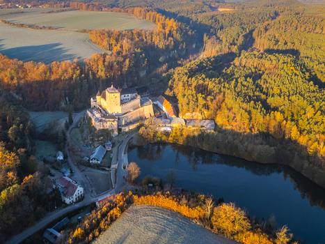 Aerial view of Kost Castle surrounded by dense autumn forests a tranquil pond and rolling hills in the golden hour light in Libosovice Kralovehradecky kraj Czechia. Aerial view of Kost Castle surrounded by dense autumn forests a tranquil pond and rolling hills in the golden hour light in Libosovice Kralovehradecky kraj Czechia.