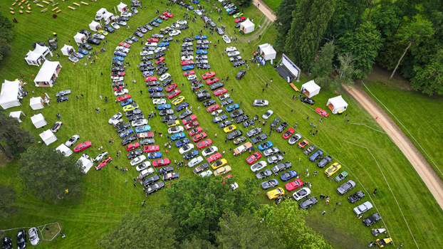 La Chapelle de Guinchay France 01 June 2024 Aerial view of a large gathering of colorful sports cars parked in curved rows on a green field with white event tents and people. La Chapelle de Guinchay France 01 June 2024 Aerial view of a large gathering of colorful sports cars parked in curved rows on a green field with white event tents and people.