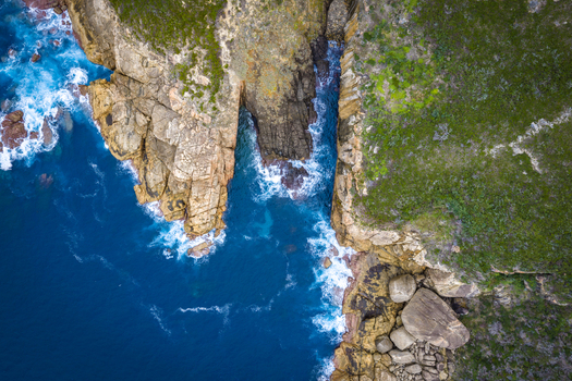 Aerial view of the rugged coastline and rocky inlet of Jimmy Newells Harbour with crashing waves and green vegetation in Albany WA Australia. Aerial view of the rugged coastline and rocky inlet of Jimmy Newells Harbour with crashing waves and green vegetation in Albany WA Australia.