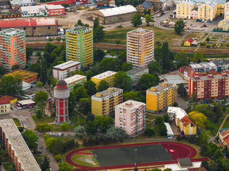 Aerial view of colorful residential apartment blocks a red water tower and a sports field with a running track surrounded by green trees in Breclav South Moravian Region Czechia.