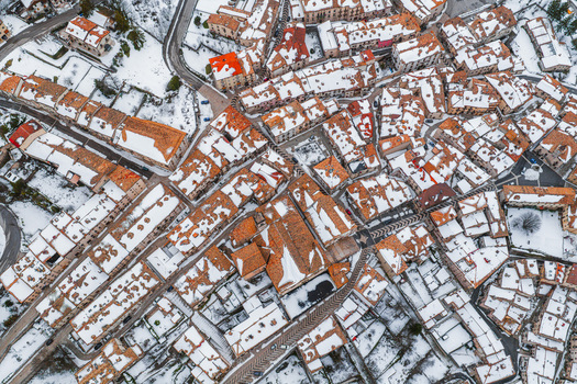 Aerial view of the historic village of Pescocostanzo with snow covered terracotta rooftops and narrow stone streets in Pescocostanzo Abruzzo Italy.