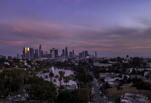 Aerial view of the sun s golden kiss upon the city s skyscrapers juxtaposed against the tranquil lake and the soft hues of the dawn sky Los Angeles California United States.