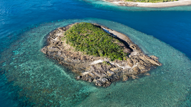 Aerial view of Haslewood Island surrounded by vibrant turquoise coral reefs and clear blue waters in the Whitsundays Queensland Australia. Aerial view of Haslewood Island surrounded by vibrant turquoise coral reefs and clear blue waters in the Whitsundays Queensland Australia.