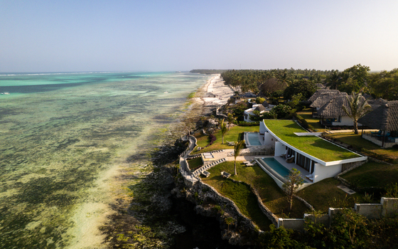 Aerial view of turquoise waters meet the shore by buildings with green roofs a tranquil scene of coastal serenity Paje Unguja South Region Tanzania.