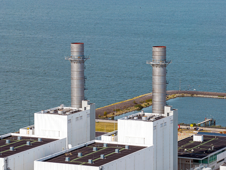 Aerial view of the Maxima power plant with its twin chimneys and industrial facilities located along the water in Lelystad Flevoland Netherlands. Aerial view of the Maxima power plant with its twin chimneys and industrial facilities located along the water in Lelystad Flevoland Netherlands.