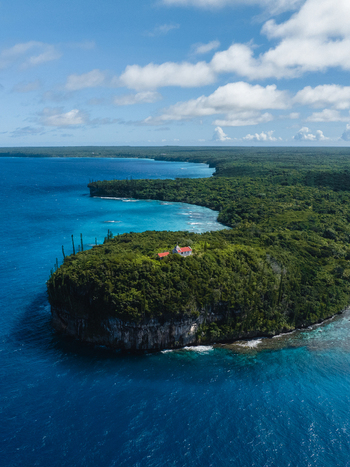 Aerial view of a church perched on a cliff embraced by lush green forest contrasting with the deep blue sea Lifou New Caledonia. Aerial view of a church perched on a cliff embraced by lush green forest contrasting with the deep blue sea Lifou New Caledonia.