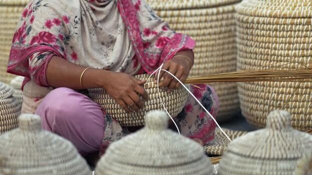 View of a woman weaving traditional straw baskets Bangladesh. View of a woman weaving traditional straw baskets Bangladesh.