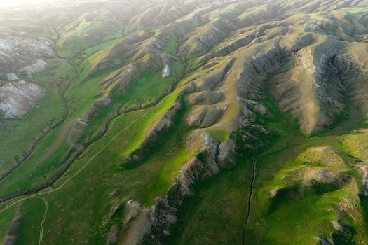 Aerial view of the rugged Airakty mountains featuring vibrant green slopes and deep shadows in the vast landscape of Shetpe Mangystau Region Kazakhstan.