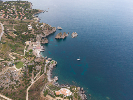 Aerial view of the rugged coastline near Palermo featuring dramatic cliffs turquoise waters a small sailboat and Mediterranean villas nestled along the shore in Palermo Sicily Italy. Aerial view of the rugged coastline near Palermo featuring dramatic cliffs turquoise waters a small sailboat and Mediterranean villas nestled along the shore in Palermo Sicily Italy.
