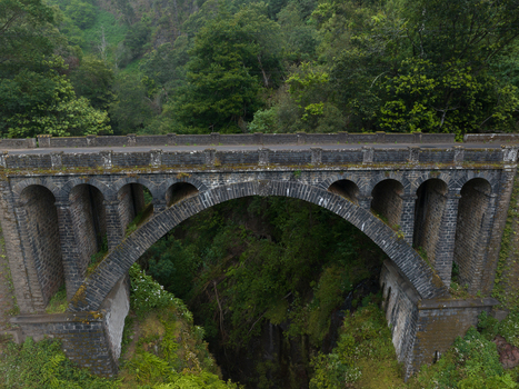 Aerial view of an old stone arch bridge spanning a deep lush forested ravine in Madeira. Aerial view of an old stone arch bridge spanning a deep lush forested ravine in Madeira.