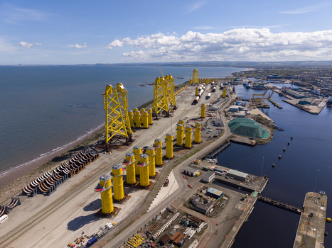 Edinburgh United Kingdom 06 May 2026 Aerial view of the dockside featuring large yellow offshore wind turbine foundations stored at the port under a clear blue sky. Edinburgh United Kingdom 06 May 2026 Aerial view of the dockside featuring large yellow offshore wind turbine foundations stored at the port under a clear blue sky.