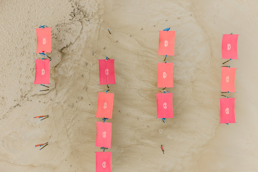Aerial view of pink sunshades arranged in rows on the sandy beach at Praia de Sao Pedro de Moel in Marinha Grande Leiria Portugal. Aerial view of pink sunshades arranged in rows on the sandy beach at Praia de Sao Pedro de Moel in Marinha Grande Leiria Portugal.