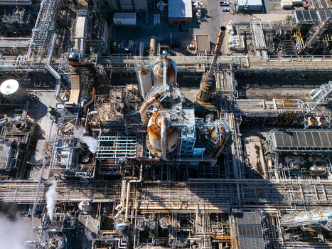 Aerial view of an industrial oil refinery featuring complex piping networks tall processing towers and storage tanks in Carson California United States.