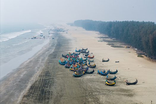 Cox s Bazar Bangladesh 10 March 2026 Aerial view of colorful moon shaped fishing boats parked on the sandy shore of the world s longest natural sea beach under a hazy sky. Cox s Bazar Bangladesh 10 March 2026 Aerial view of colorful moon shaped fishing boats parked on the sandy shore of the world s longest natural sea beach under a hazy sky.