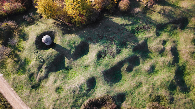 Aerial view of the historic World War I battlefield featuring numerous shell craters grassy terrain and autumn trees in Douaumont Vaux Grand Est France.