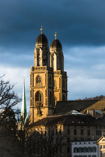 Zurich Switzerland 02 April 2023 View of the majestic Grossmünster church towers piercing the skyline its sandstone facade glowing warmly against the dramatic backdrop of a stormy sky. Zurich Switzerland 02 April 2023 View of the majestic Grossmünster church towers piercing the skyline its sandstone facade glowing warmly against the dramatic backdrop of a stormy sky.