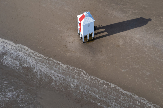 Aerial view of the Burnham on Sea Low Lighthouse on wooden stilts on the sandy beach at low tide with its long shadow cast across the wet sand Burnham on Sea England United Kingdom.