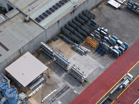 Aerial view of industrial site with rows of stored metal components factory buildings with solar panels on the roof and a loading area with a truck Melbourne VIC Australia.
