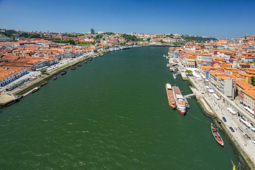 Aerial view of terracotta rooftops cascade down to the serpentine Douro River where boats rest near Ribeira district Porto Porto District Portugal. Aerial view of terracotta rooftops cascade down to the serpentine Douro River where boats rest near Ribeira district Porto Porto District Portugal.