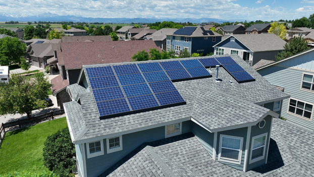 Aerial view of a house with solar panels on the roof in a suburban neighborhood surrounded by trees and other homes in Fort Collins Colorado United States. Aerial view of a house with solar panels on the roof in a suburban neighborhood surrounded by trees and other homes in Fort Collins Colorado United States.