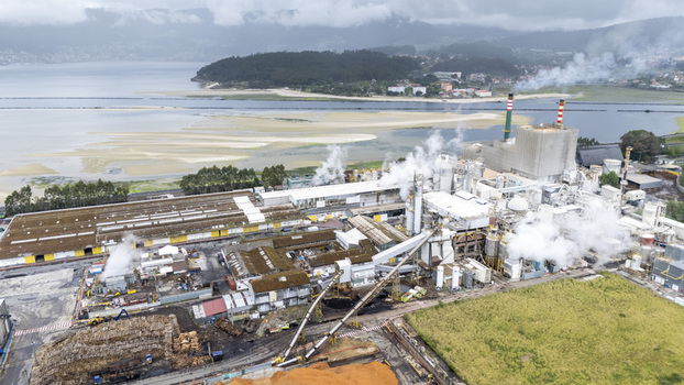 Aerial view of Biofabrica de Ence en Pontevedra with smoking chimneys and industrial structures near the estuary under a cloudy sky Pontevedra Pontevedra Spain. Aerial view of Biofabrica de Ence en Pontevedra with smoking chimneys and industrial structures near the estuary under a cloudy sky Pontevedra Pontevedra Spain.