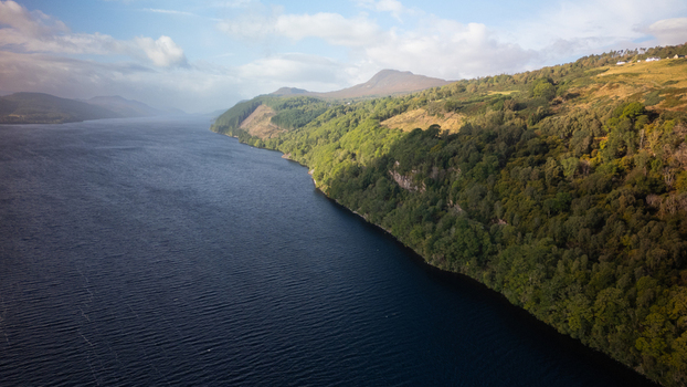 Aerial view of Loch Ness with its deep blue waters lush green forested hills and rolling landscape in Highland Council Scotland United Kingdom.