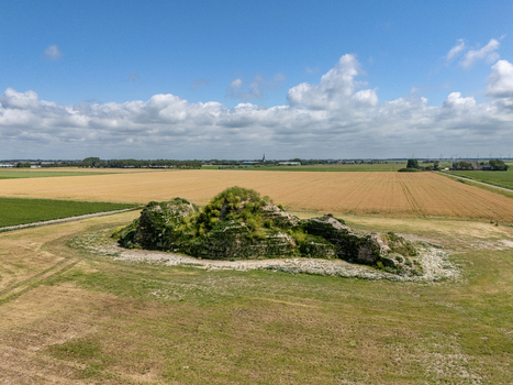 Aerial view of the Dijk van een wijf sculpture a grassy mound structure set in a vast agricultural field under a bright blue sky with scattered clouds in Oosterbierum Friesland Netherlands. Aerial view of the Dijk van een wijf sculpture a grassy mound structure set in a vast agricultural field under a bright blue sky with scattered clouds in Oosterbierum Friesland Netherlands.