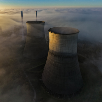 Aerial view of the RWE Clauscentrale power plant cooling towers rising above a thick layer of morning fog during sunrise in Maasbracht Limburg Netherlands. Aerial view of the RWE Clauscentrale power plant cooling towers rising above a thick layer of morning fog during sunrise in Maasbracht Limburg Netherlands.