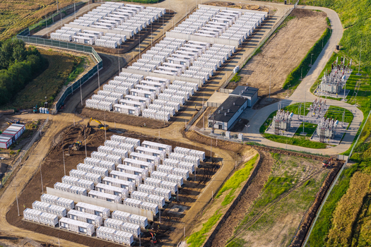 Aerial view of a large battery storage facility featuring rows of white containers electrical transformers and switchgear in Poland.