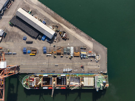 Aerial view of a cargo ship docked at the industrial port surrounded by shipping containers warehouses and heavy machinery in Bajos de Haina San Cristobal Provinc Dominican Republic.