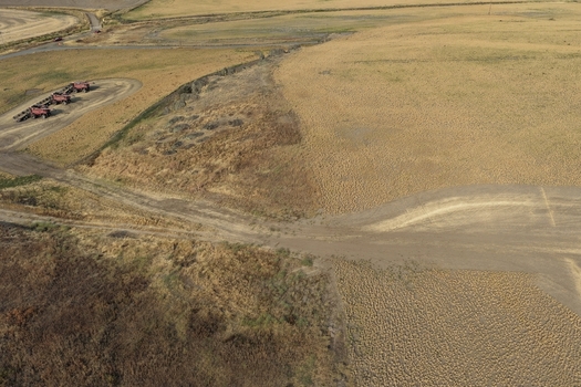 Aerial view of the rolling hills and golden agricultural fields of the Palouse region with dirt roads and farm equipment in Palouse Washington United States. Aerial view of the rolling hills and golden agricultural fields of the Palouse region with dirt roads and farm equipment in Palouse Washington United States.