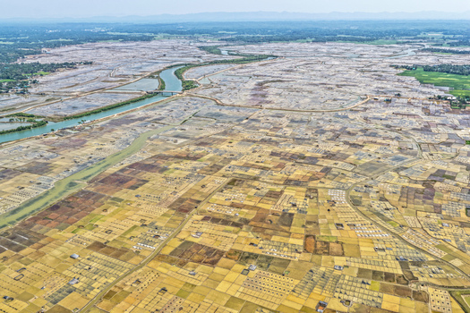 Aerial view of the landscape of salt fields with a river snaking through contrasting with the earth tones of the fields Cox s Bazar Chittagong Division Bangladesh. Aerial view of the landscape of salt fields with a river snaking through contrasting with the earth tones of the fields Cox s Bazar Chittagong Division Bangladesh.