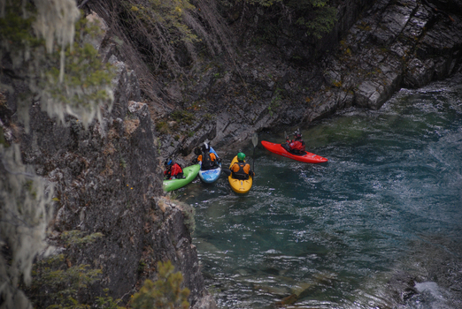 View of kayakers paddling through the turquoise waters of the Rio Manso canyon surrounded by rugged rocky cliffs and lush forest San Carlos de Bariloche Rio Negro Argentina. View of kayakers paddling through the turquoise waters of the Rio Manso canyon surrounded by rugged rocky cliffs and lush forest San Carlos de Bariloche Rio Negro Argentina.