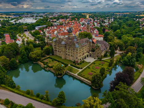 Aerial view of Schloss Neuenstein surrounded by a moat manicured gardens and historic architecture in the town of Neuenstein Baden Wurttemberg Germany. Aerial view of Schloss Neuenstein surrounded by a moat manicured gardens and historic architecture in the town of Neuenstein Baden Wurttemberg Germany.