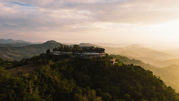 Aerial view of the Temple of Leah in Busay nestled among lush green hills and tropical forests during a golden sunset in Cebu City Central Visayas Philippines.