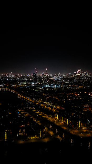 Aerial view of the illuminated London skyline at night featuring skyscrapers glowing against the dark sky with city lights along the Thames London England United Kingdom. Aerial view of the illuminated London skyline at night featuring skyscrapers glowing against the dark sky with city lights along the Thames London England United Kingdom.