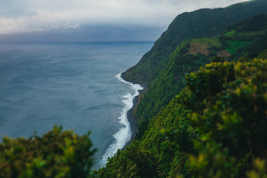 Aerial view of the dramatic coastline where the deep blue sea crashes against the rugged cliffs of the Azores Azores Portugal.