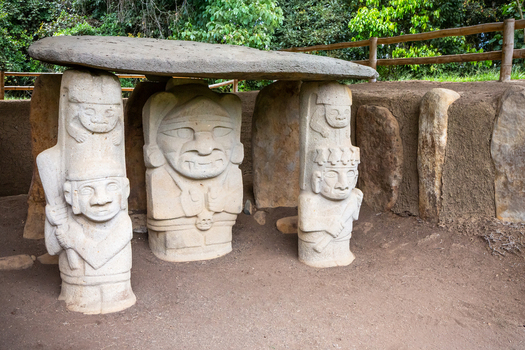 View of the ancient stone statues at San Agustin Archaeological Park featuring intricate pre Columbian carvings under a stone slab roof in San Agustin Huila Colombia.