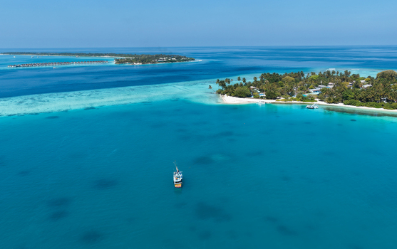 Aerial view of the island of Vaanee surrounded by turquoise lagoon waters coral reefs and lush tropical vegetation in Vaanee Dhaalu Atoll Maldives. Aerial view of the island of Vaanee surrounded by turquoise lagoon waters coral reefs and lush tropical vegetation in Vaanee Dhaalu Atoll Maldives.
