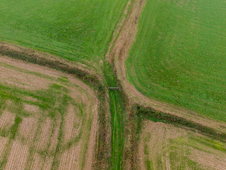 Aerial view of agricultural farmland featuring green fields freshly harvested brown fields traditional hedgerows and dirt tracks in Looe Cornwall United Kingdom. Aerial view of agricultural farmland featuring green fields freshly harvested brown fields traditional hedgerows and dirt tracks in Looe Cornwall United Kingdom.