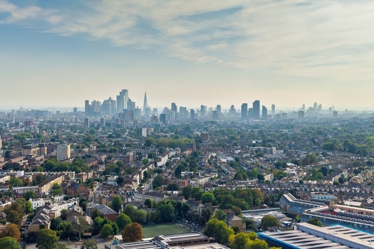 Aerial view of the London skyline featuring the Shard and various skyscrapers rising above the dense residential rooftops and green spaces of Stoke Newington in London England United Kingdom. Aerial view of the London skyline featuring the Shard and various skyscrapers rising above the dense residential rooftops and green spaces of Stoke Newington in London England United Kingdom.