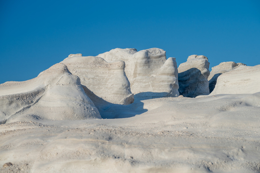 View of the unique white volcanic rock formations of Sarakiniko Beach under a clear blue sky in Milos Greece. View of the unique white volcanic rock formations of Sarakiniko Beach under a clear blue sky in Milos Greece.