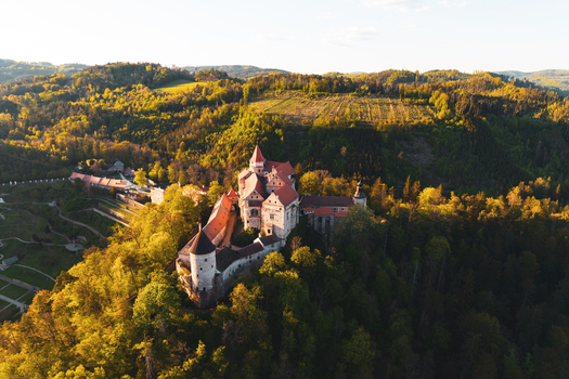 Aerial view of Pernstejn Castle surrounded by lush green forests and rolling hills in the golden hour light in Nedvedice Jihomoravsky kraj Czechia. Aerial view of Pernstejn Castle surrounded by lush green forests and rolling hills in the golden hour light in Nedvedice Jihomoravsky kraj Czechia.